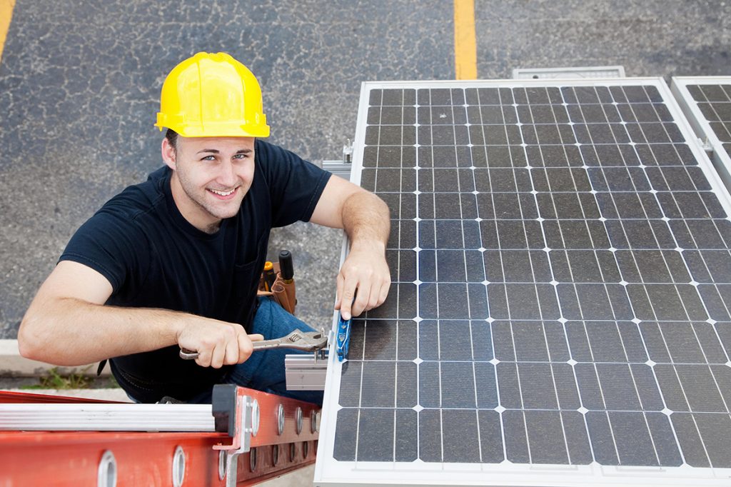électricien installant des panneaux solaires sur le toit d'un immeuble